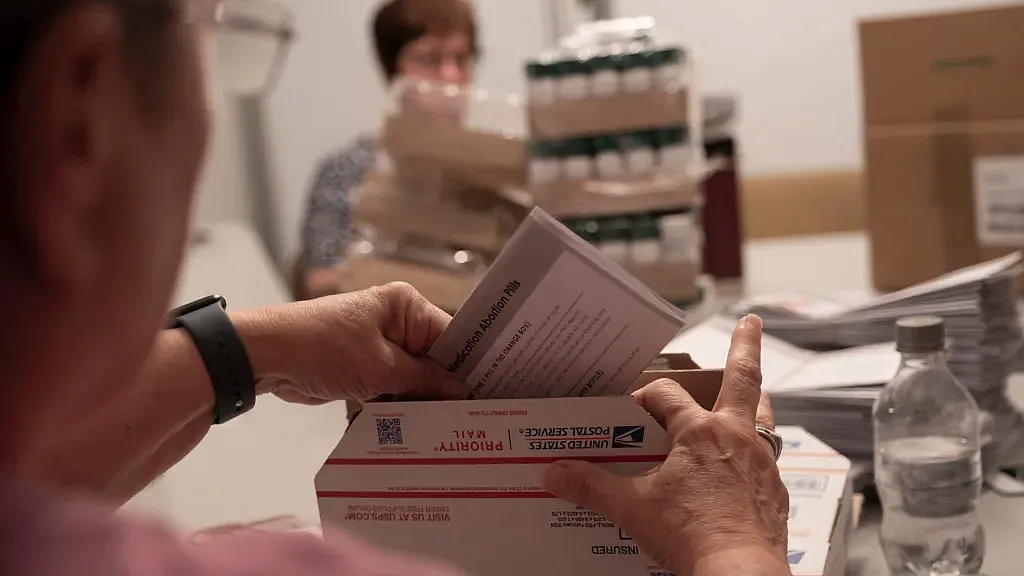 Volunteers at an abortion pill provider work around a conference table to pack 500 boxes to be sent to people in all 50 states. 