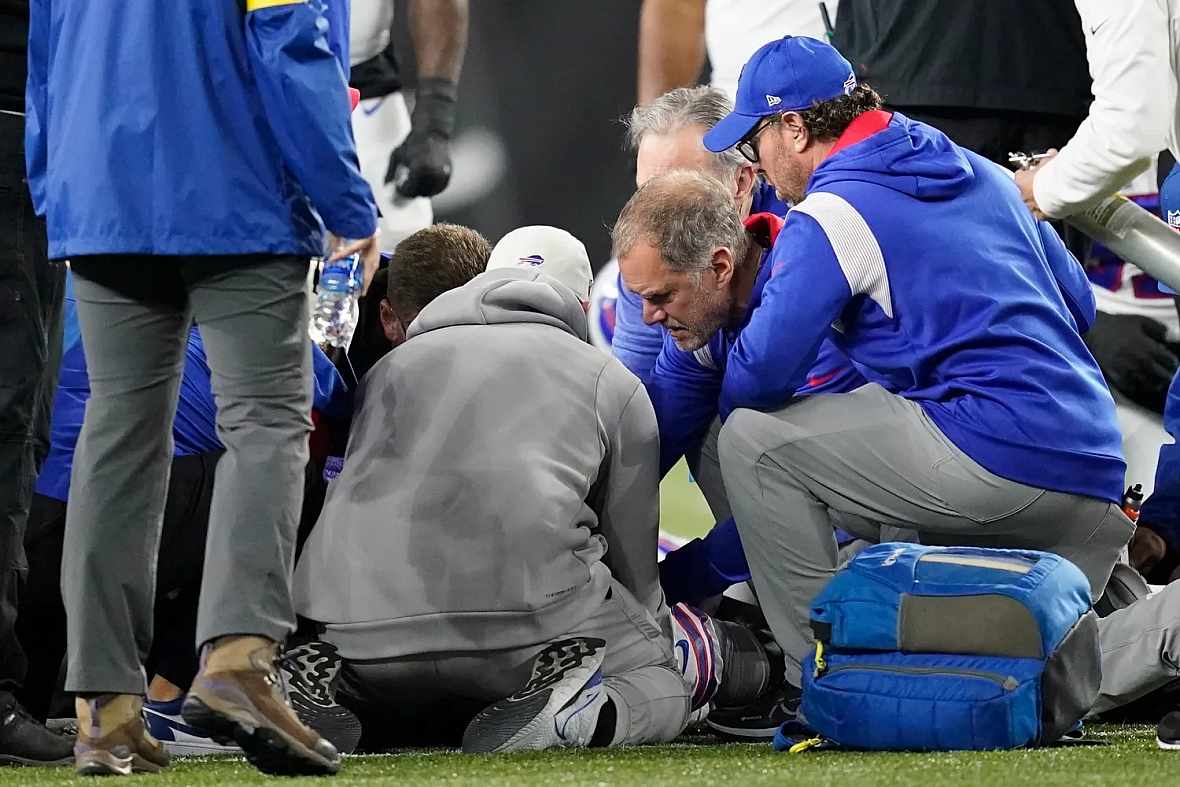 Coaches attend to a hurt player on the football field.