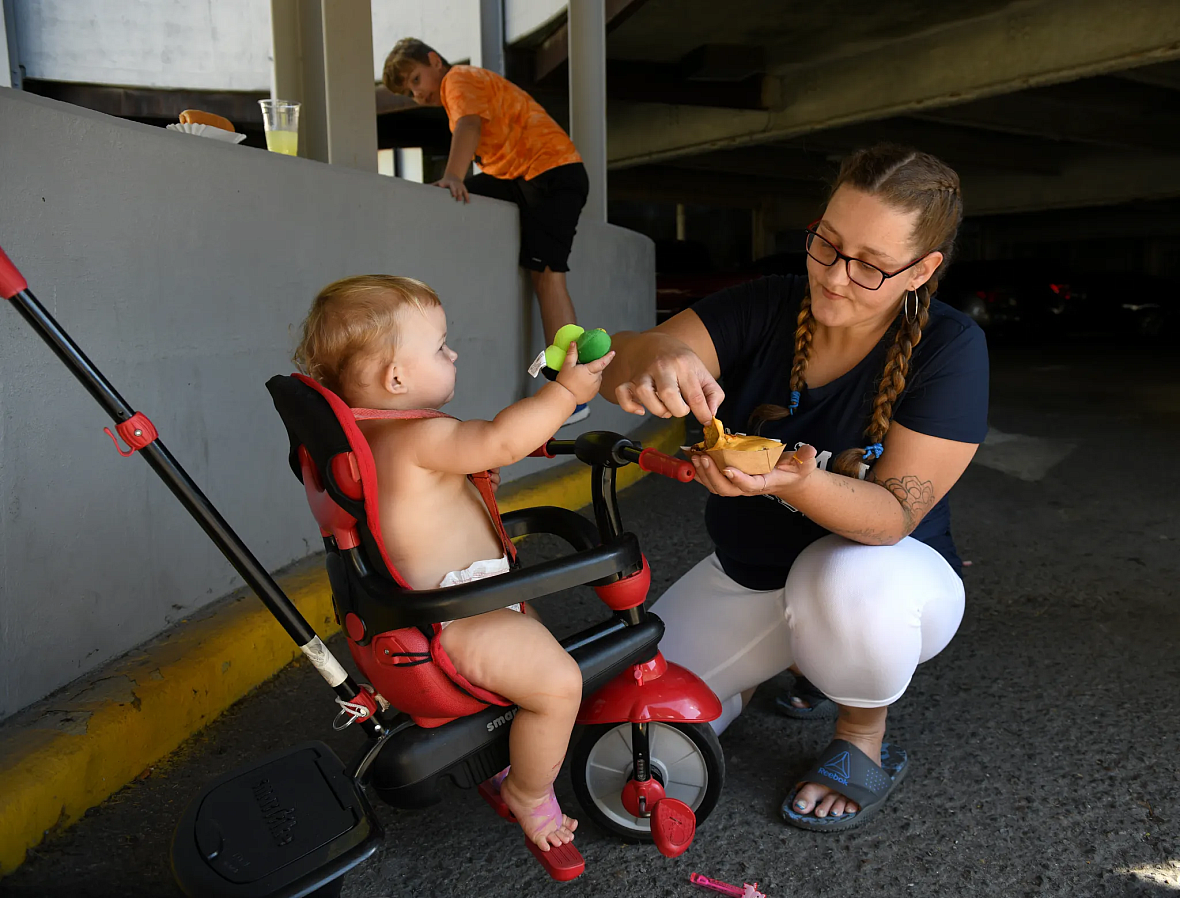 Person kneeling by a child in a stroller