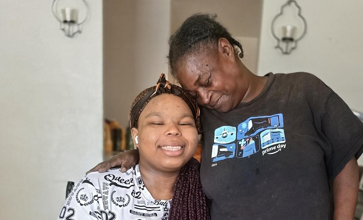 A Black woman embraces her granddaughter, who wears a prosthetic leg, in their Kern County home.