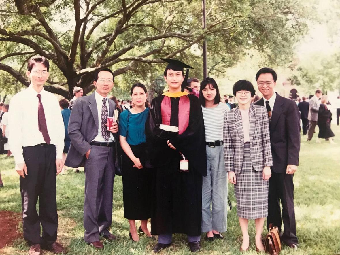Group of people, one of whom is in a graduation cap and gown