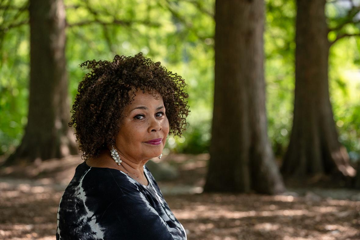 Image of a black woman sitting in front of trees