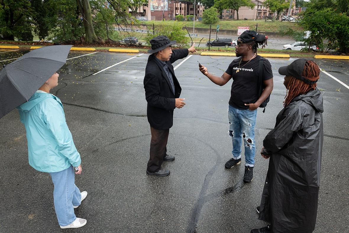 Person speaking into mic held by another person, as 2 more watch