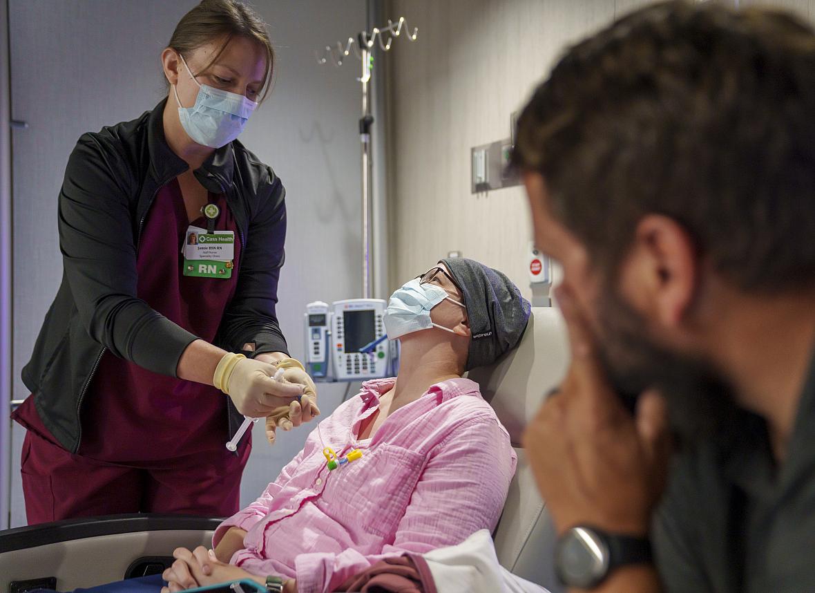 A nurse administrating medicines to a patient while a visitor watches