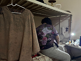 A person sitting on a bed facing away