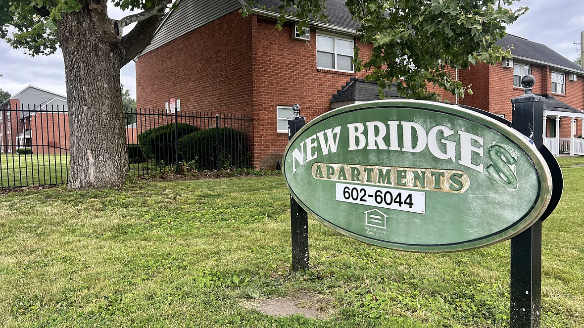 Lawn in front of red brick buildings with green sign