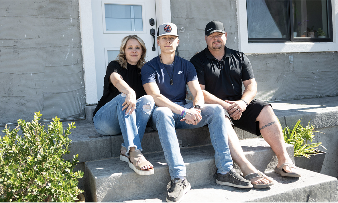 3 people seated on stairs in front of a door