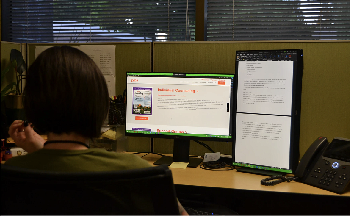 Person seated in front of a 2 monitors