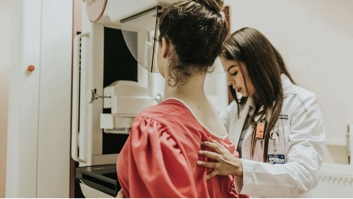A female doctor helps another woman get a mammogram