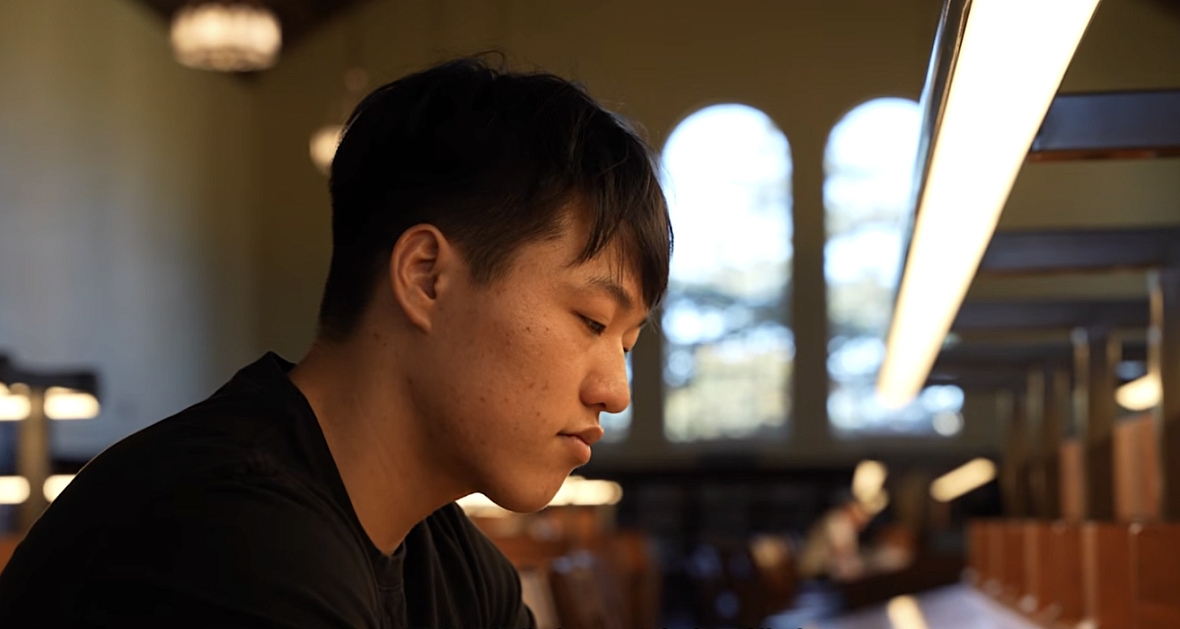 A young Korean man sits in a library