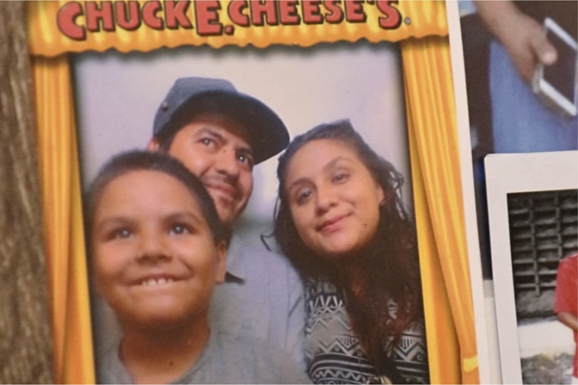 Alma Ramirez, her partner José, and their seven-year-old son smile inside a photobooth at Chuck E. Cheese’s. 