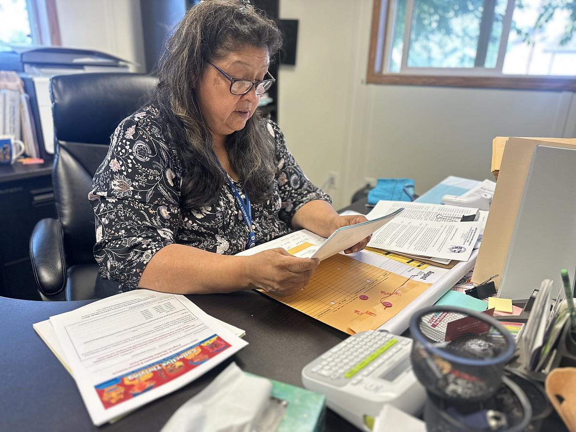 Image of a women sitting at her office desk looking over a document