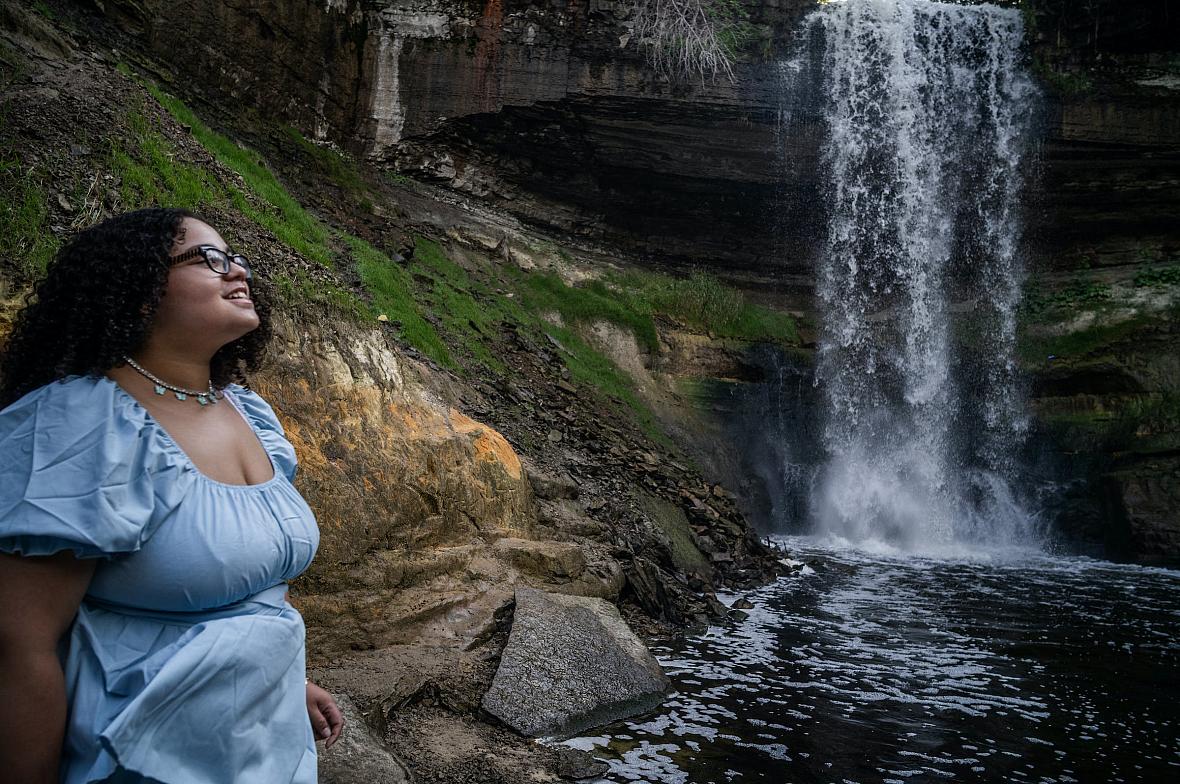 A girl standing near a waterfall