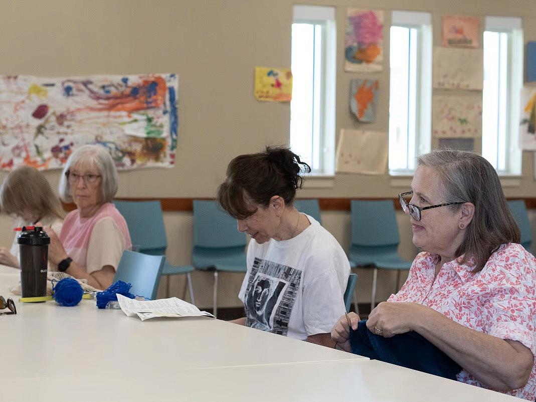 People sitting knitting in a room