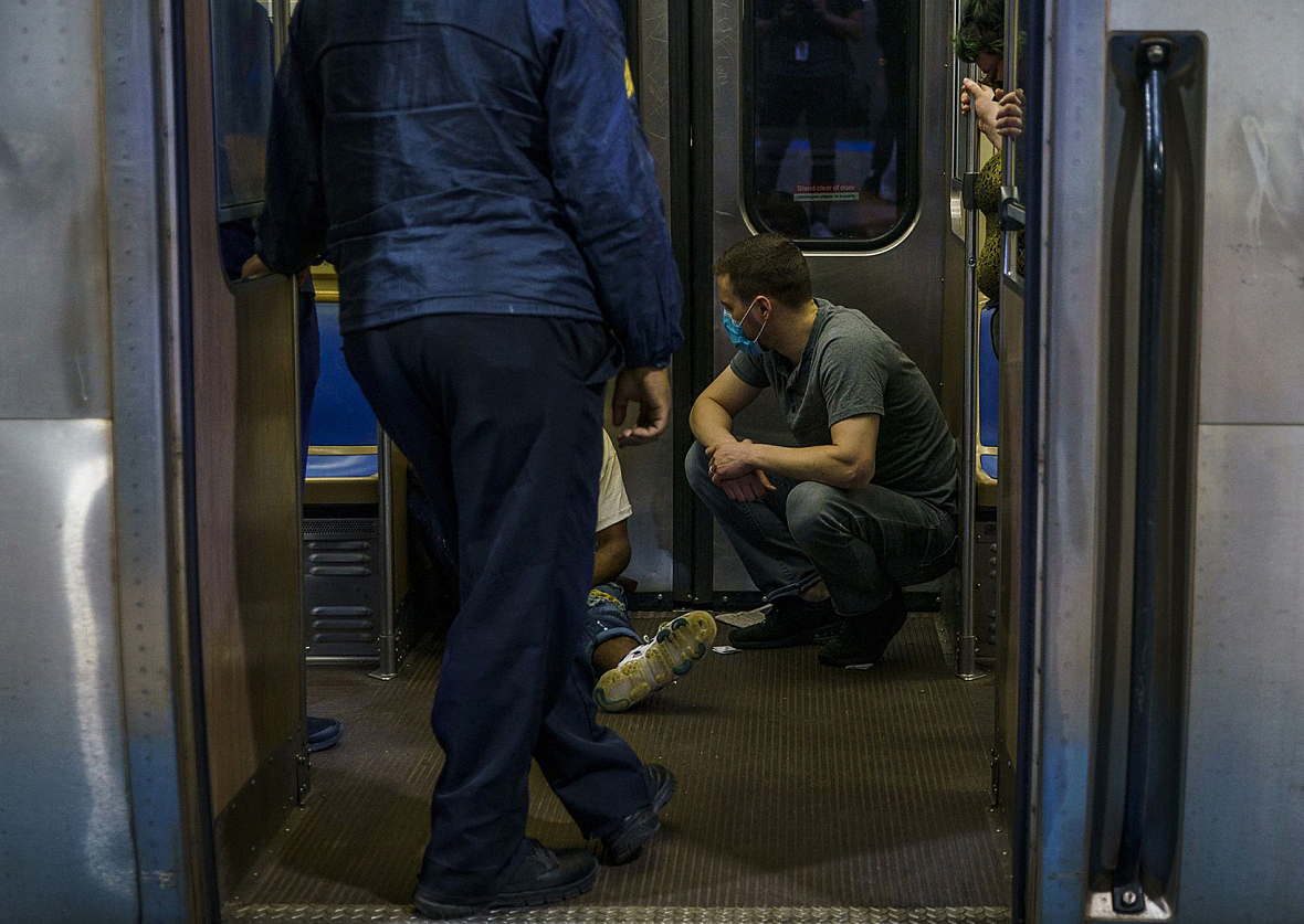 Person squatting in a train next to another person