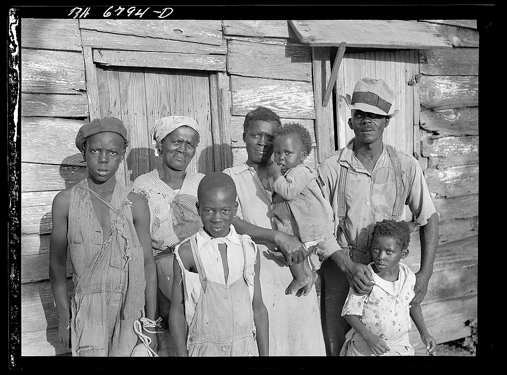 Multiple people standing in front of a wooden hut