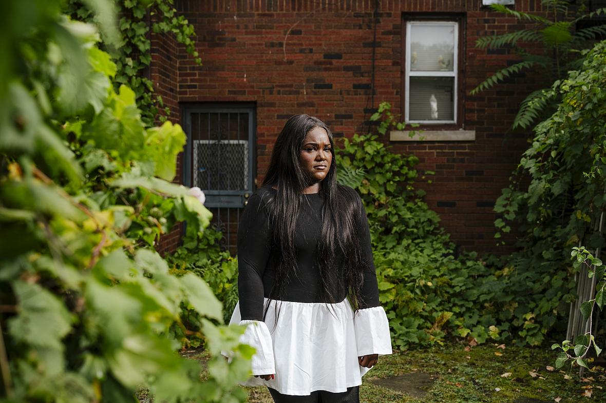 A person in black and white dress standing against a tree