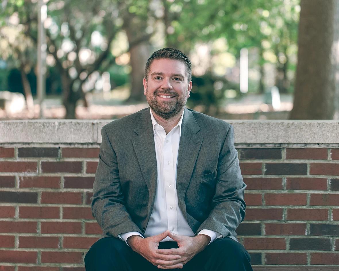 A man sitting against a wall, smiling