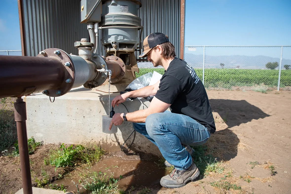 Person working on a farm and collecting water from pipe