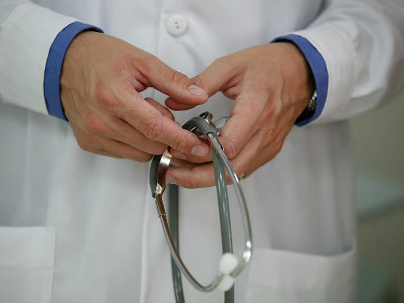 Person wearing white lab coat and holding a stethoscopes