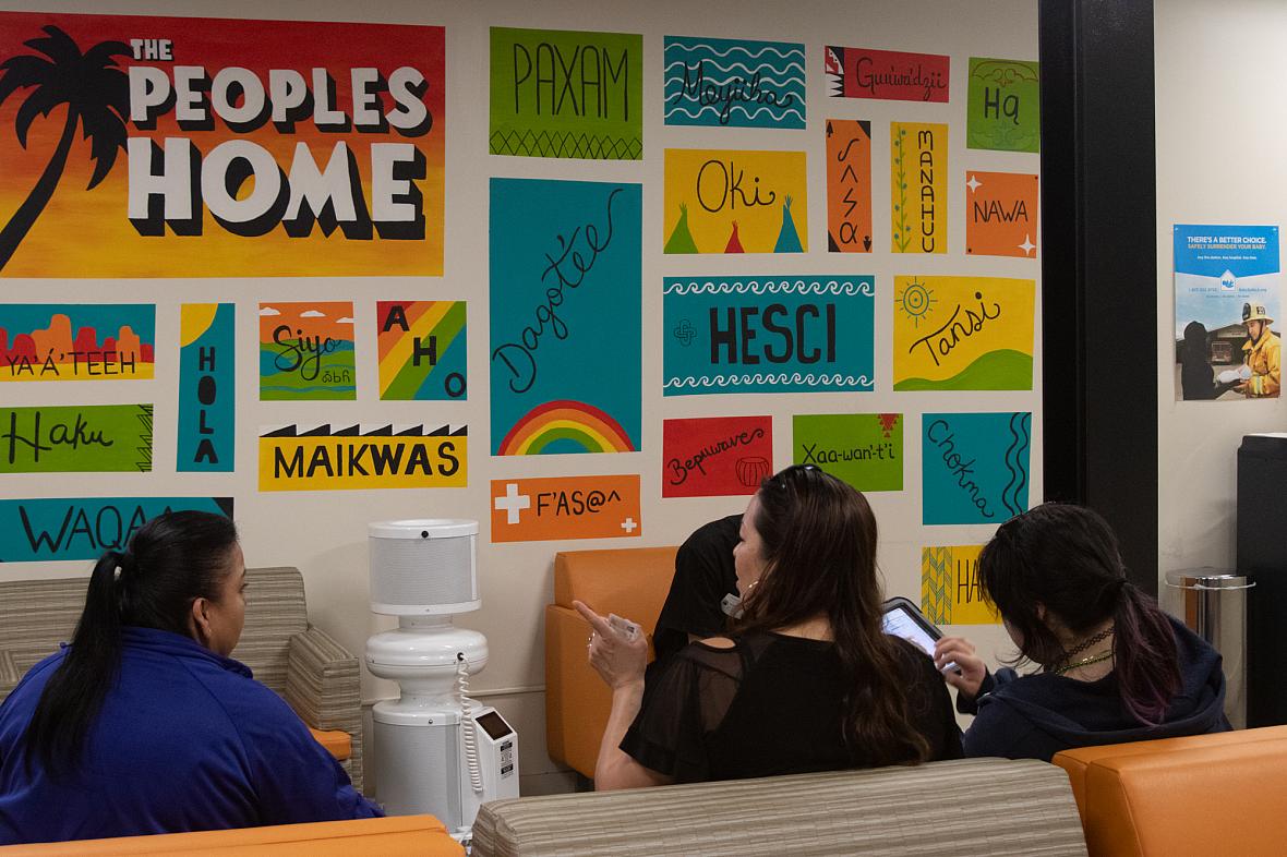 Three women wait in the colorful waiting room of UAII in Echo Park, Los Angeles