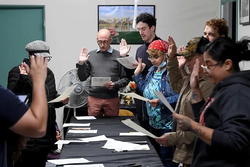 Image of people standing around table swearing