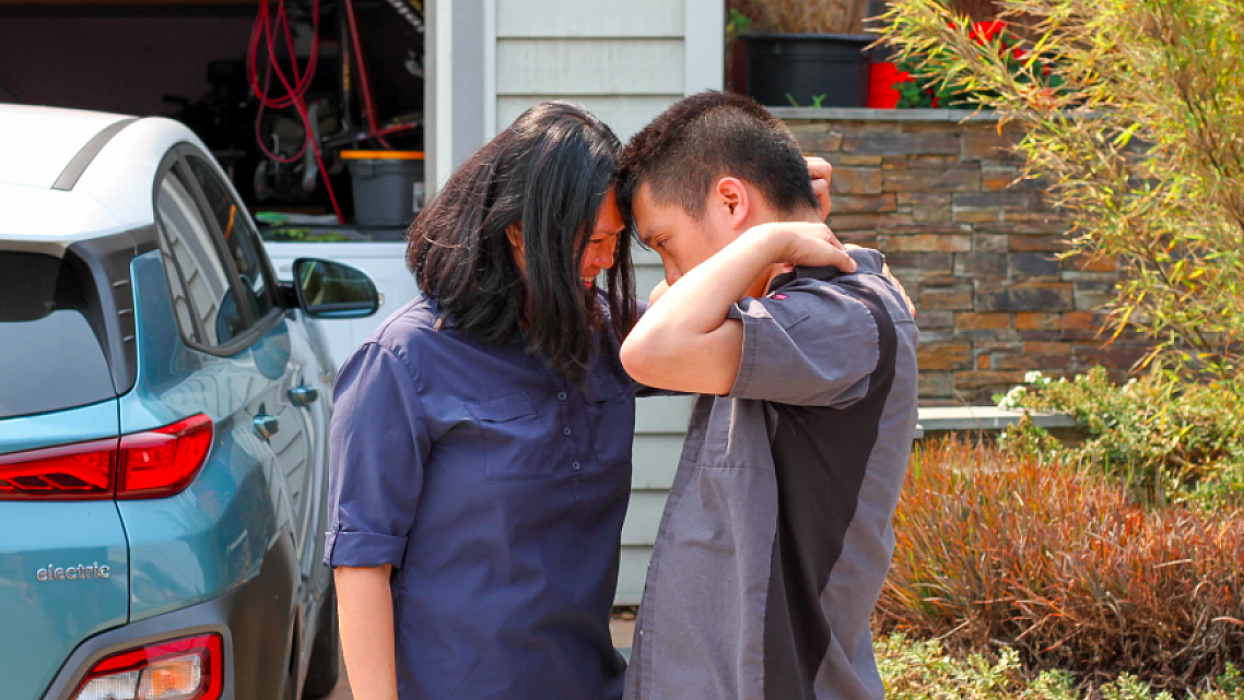 Mother and son talking together in their driveway.