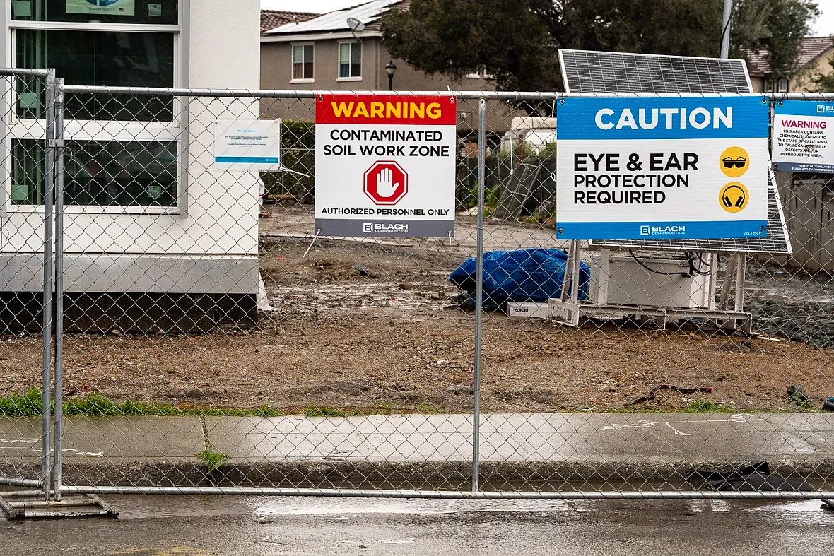Warning signs posted on a fence at a construction site.