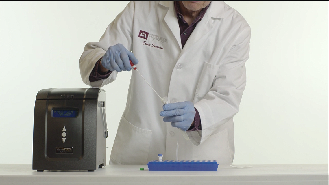 A lab technician works with a cocci sample to be used in a new testing instrument developed by DxNA LLC. that promises rapid, accurate detection.The specimen would be inserted into the machine, pictured to the left, and a diagnosis would be determined in about two hours. CREDIT: DxNA LLC