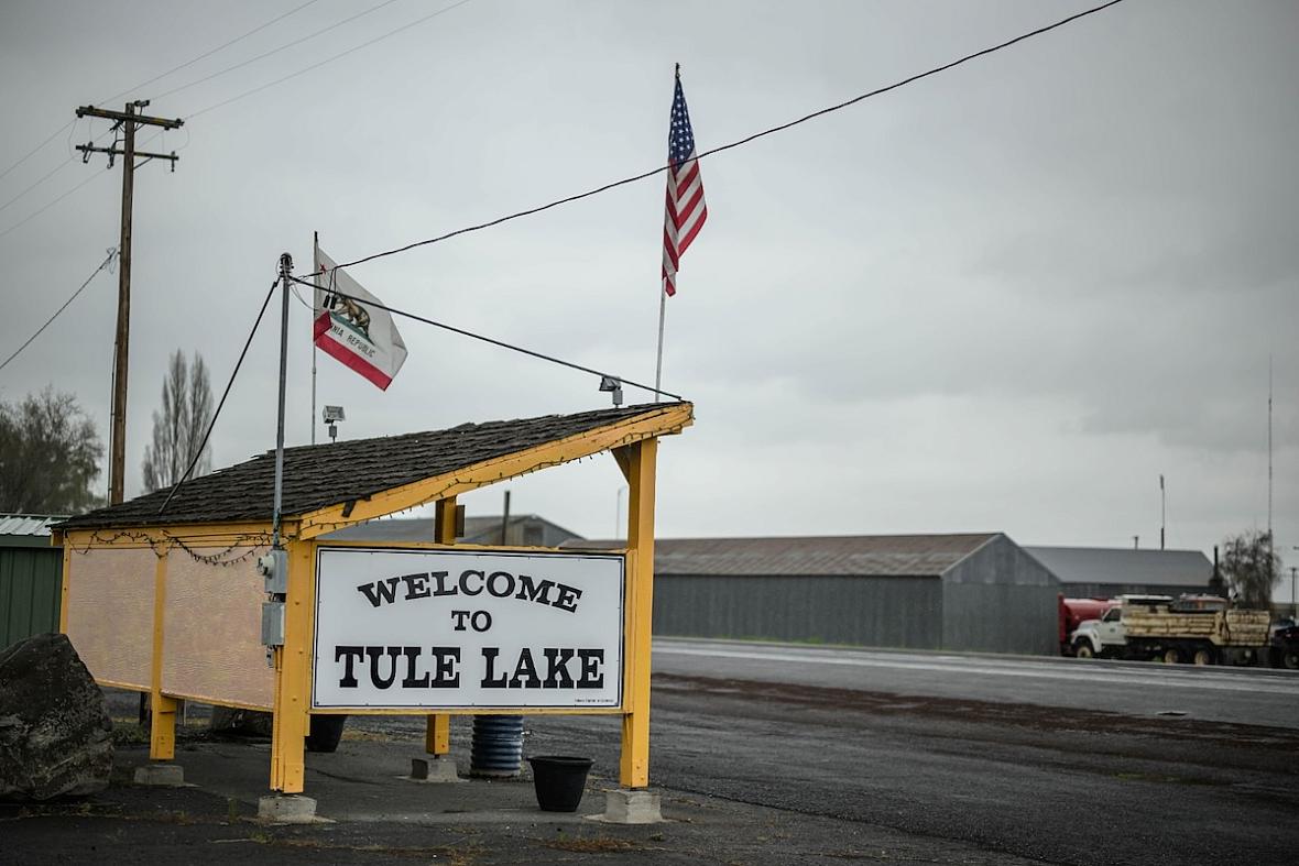 Welcome sign and 2 American flags by a road