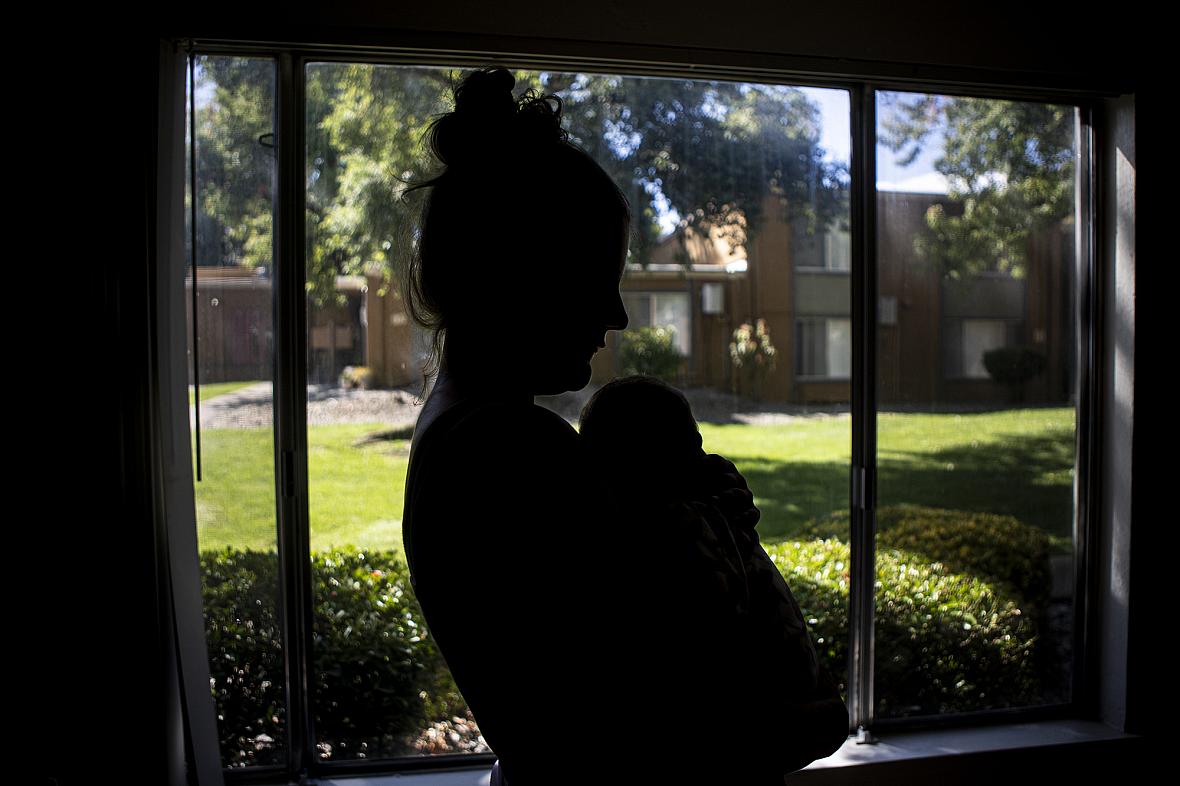 A formerly homeless mother, Cassidy, holds her child in her apartment in Redding on Sept. 20, 2022. Like many mothers who contra