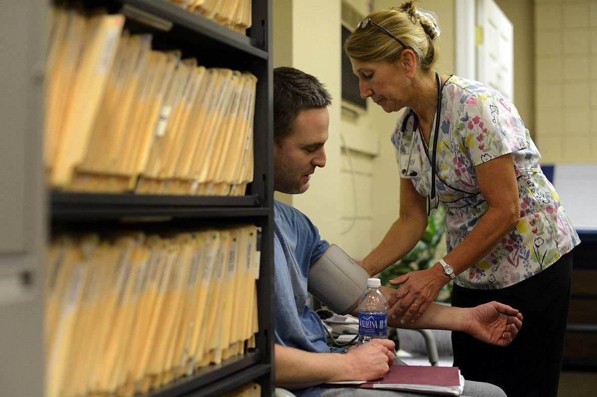 Judy Kunes, an LPN and volunteer at the 9th Street Free Clinic in McKeesport, measures the blood pressure of Nathan Hite, a former McKeesport firefighter experiencing shoulder and hip pain, on May 15, 2014. 