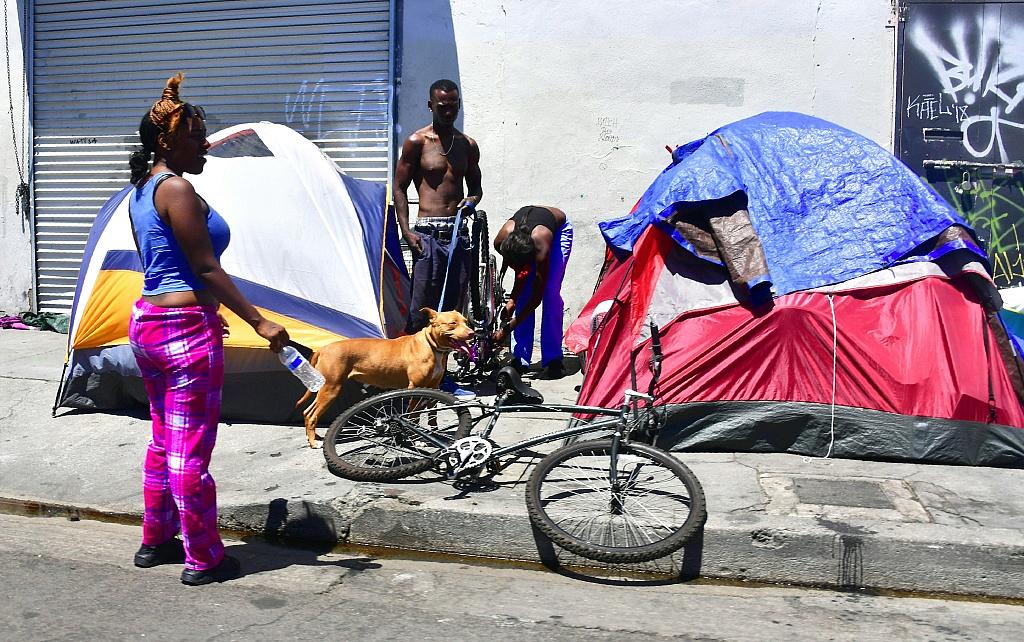 Homeless residents chat beside their tents on a street in downtown Los Angeles, California on June 25, 2018.
