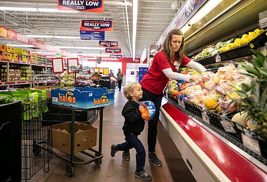 Jenny Kute and four-year-old son Henry put out fresh produce at the family's Save-A-Lot on Taylor Boulevard in the Hazelwood nei