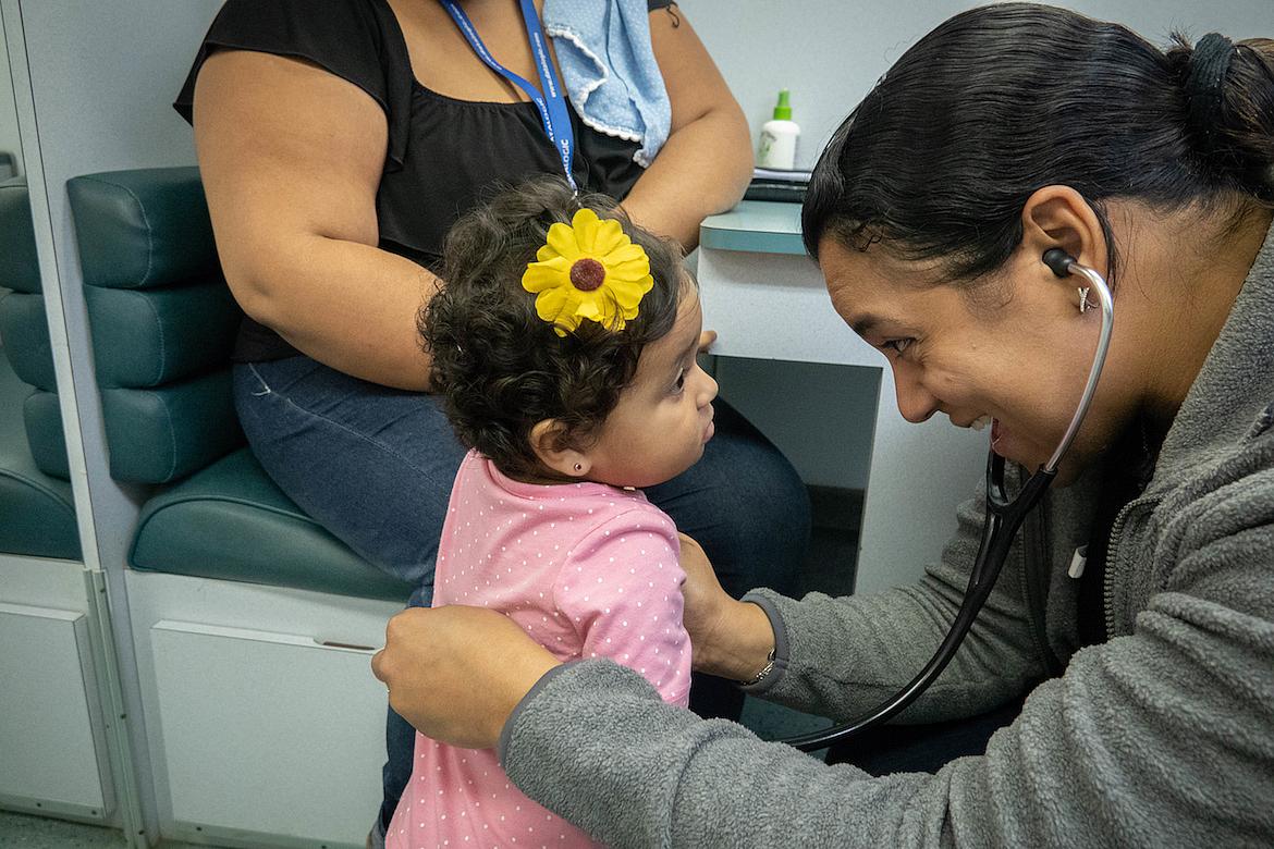 Dr. Raquel Figueras, a pediatrician, listens to toddler Siulaidali Morales’ heart and lungs during a medical exam.