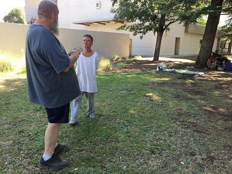 George Felix, left, and Scott Smith spend their days under the shade of large trees at a public park in Redding.