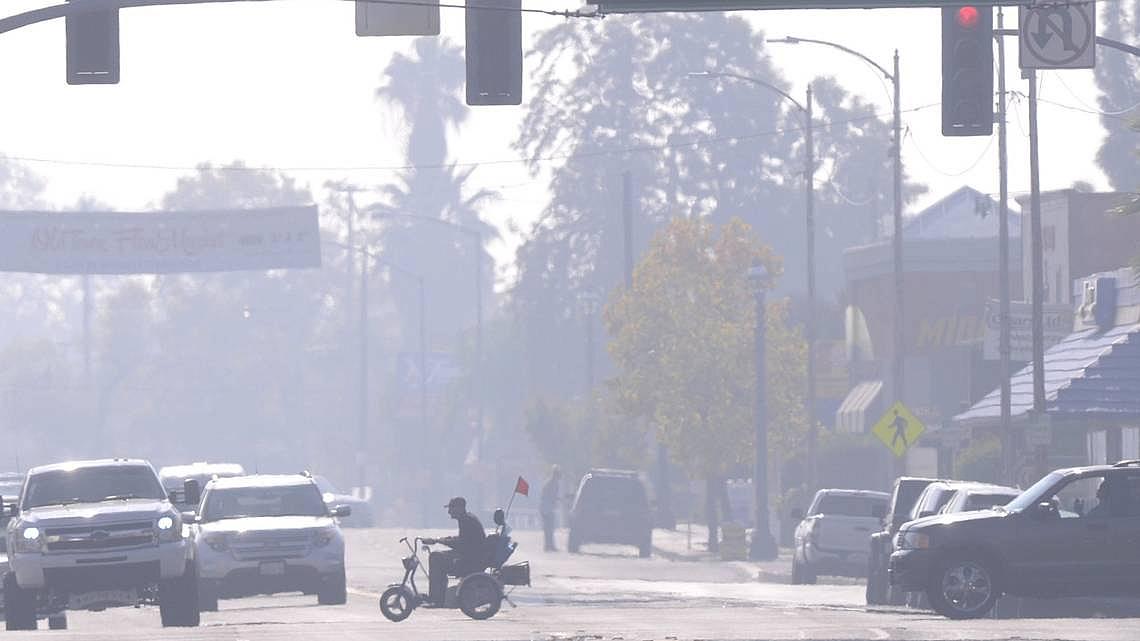 A man in a scooter rides through Old Town Clovis on a smoggy afternoon on Nov. 6, 2014.