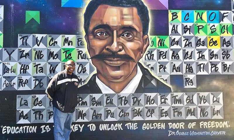 San Francisco Unified School District Superintendent Vincent Matthews stands in front of the mural at George Washington Carver E