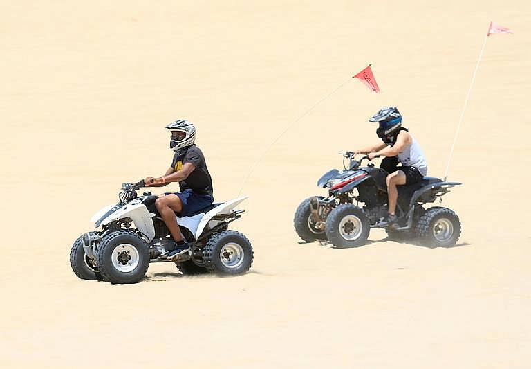 Two riders on quads ride in the OHV area of Oceano Dunes in June. Laura Dickinson