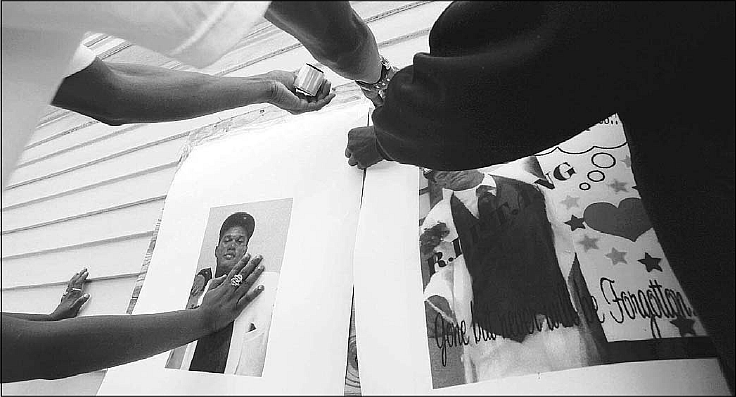 Friends of Ditiyan Franklin, 17, place posters of him Thursday at the site of his killing in Oakland. Franklin, a senior about t