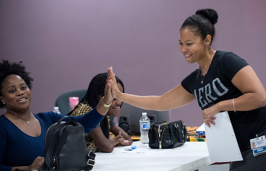 Black Infant Health program leader, Lesha Porter, right, gives a high five to Juanita O’Neal of Perris at Living Way Community C