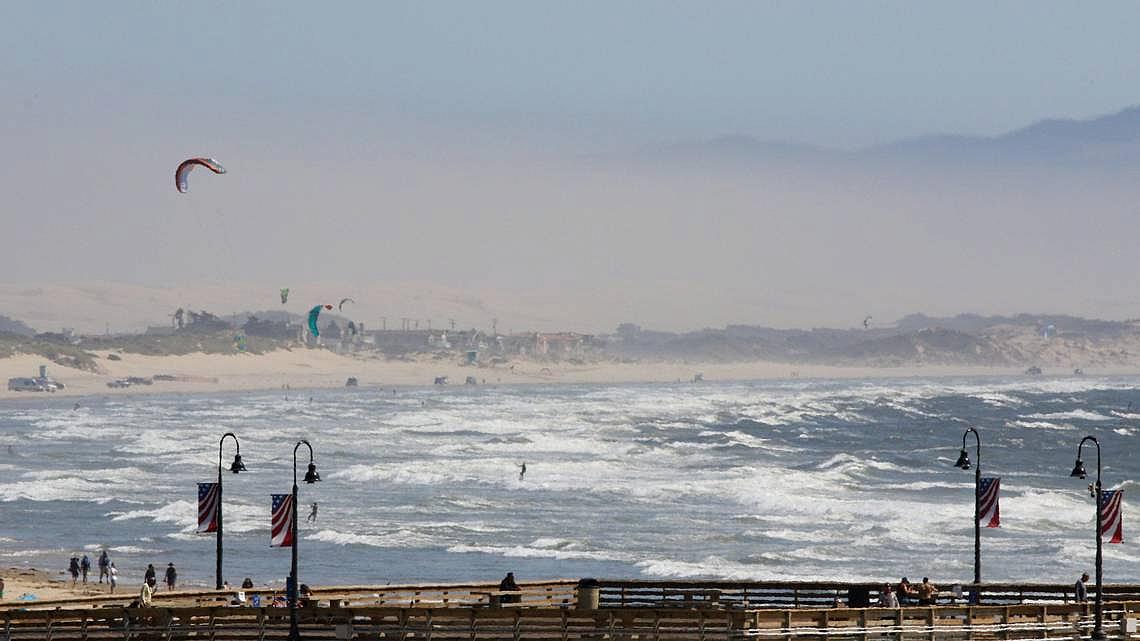 Wind brought out windsurfers south of Pismo Pier on August 21. It also contributed to a dusty haze obscuring the view.