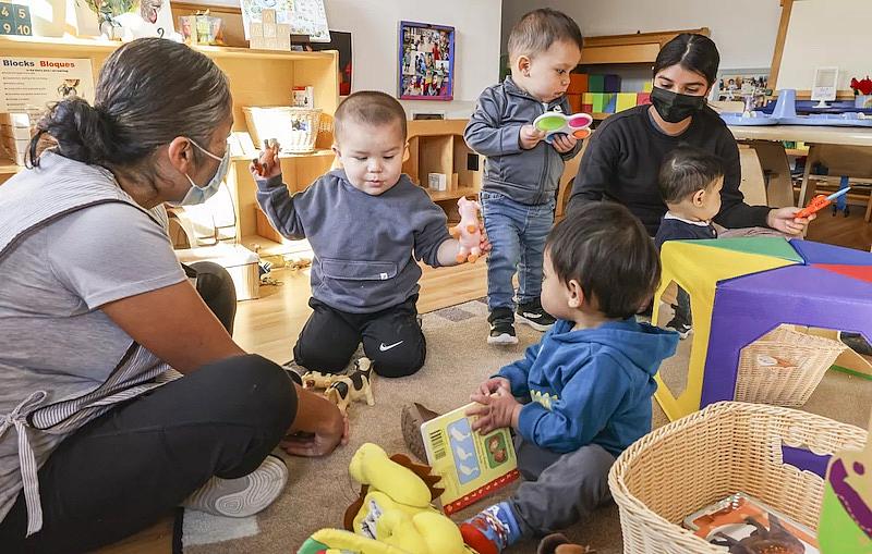 Teachers Lucy Arevalo (left) and Karina Palomino (right) play with children at Miren Algorri’s family child care.