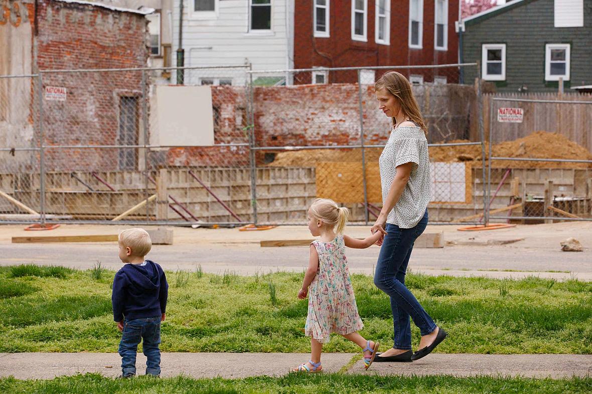 Jana Curtis and two of her children walk past one of many construction sites in their river ward neighborhood.