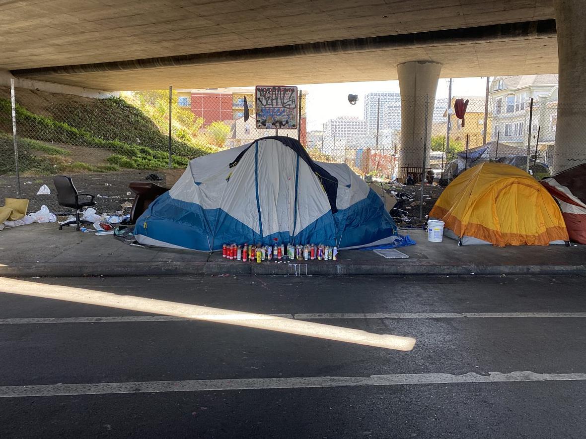 Candles create a vigil outside the tent of an unhoused community member who was shot in West Oakland