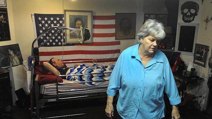 Shirley Ropka gets her son, Chuck, ready for bed at her house in Parkville. Chuck has lived in the basement of the family house ever since he was shot when he was younger.