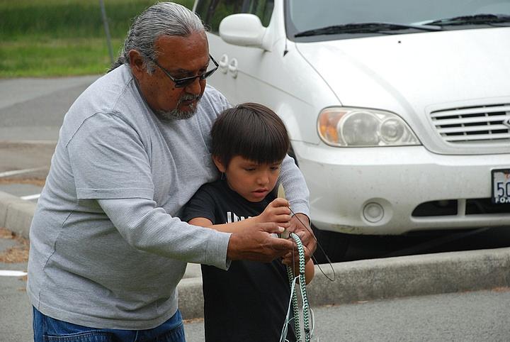 David Gensaw Sr. shows Dean McCovey how to repair a gill net at Margaret Keating Elementary School's Au Minot Day celebration.