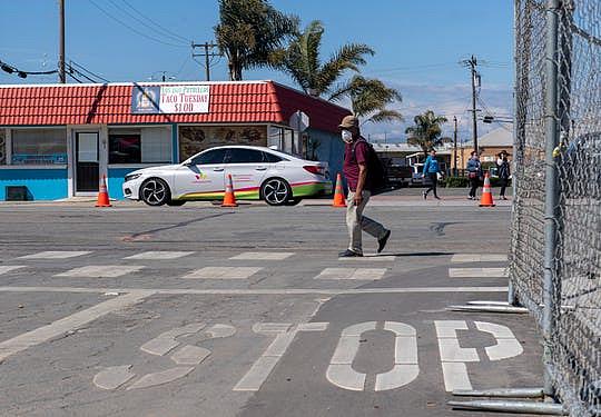 A person wearing a face mask walks by the mask distribution event on 312 E. Alisal St. on Friday, April 10, 2020.