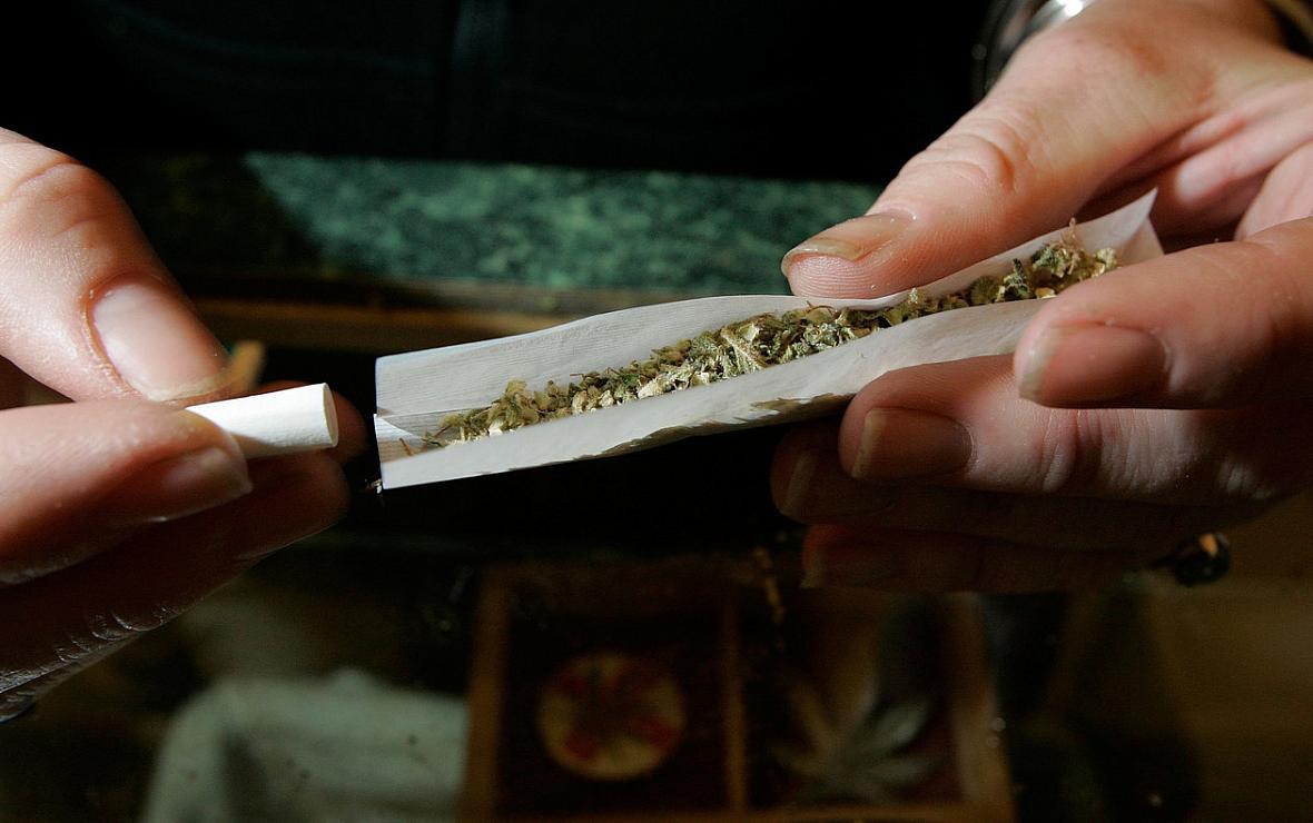 A worker at an alternative health services cannabis dispensary rolls a marijuana cigarette.