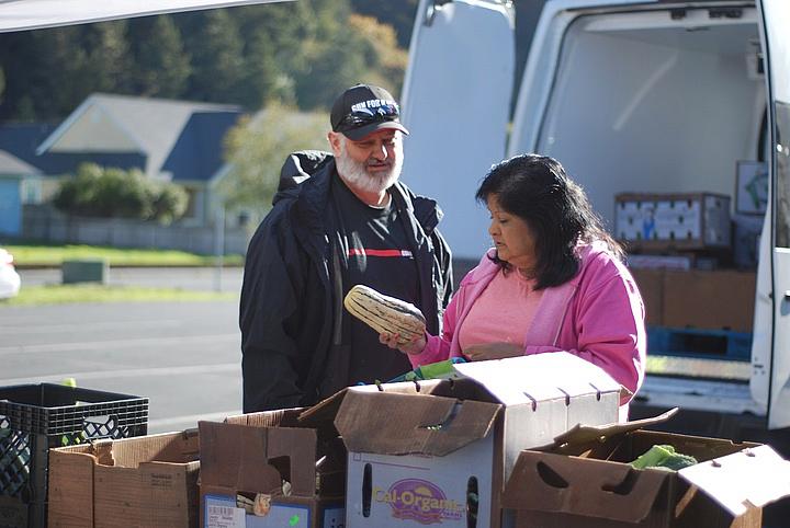 Shayne Britt and Roxie Reyes examine a delicata squash at Food For People's Mobile Produce Pantry in Klamath.